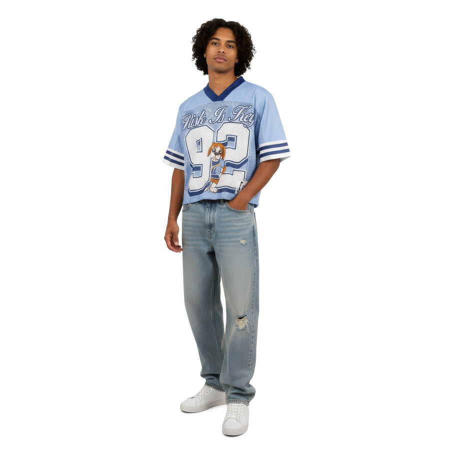 Rik the Beagle mascot sports jersey in blue and white, featuring a premium V-neck design and athletic fit, is perfect for dog lovers and sports fans. It's styled for Gen Z males, paired with jeans.