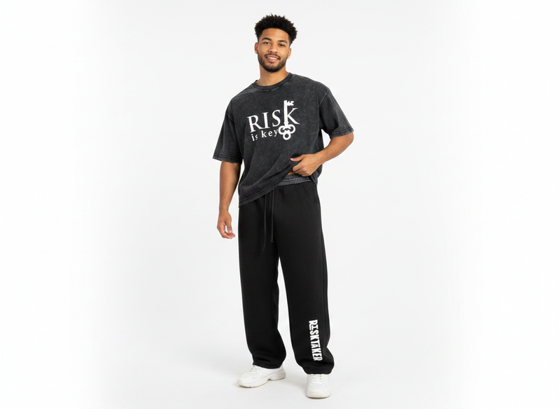 A full-body studio mockup of a male model styled in a trendy, Gen Z-inspired streetwear outfit. The model is wearing the baggy, dark fleece barrel sweatpants, which bow out naturally at the legs and gather neatly at the ankles. The signature black-and-white plaid contrast waistband is clearly visible at the waist, adding a distinct layered element to the look. The outfit is styled cohesively with a contemporary streetwear top and a pair of clean sneakers, perfectly showcasing the versatile, oversized propor