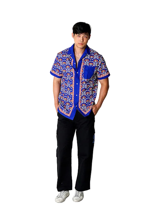 Model wearing Rik’s Pawsitive Vibes camp shirt buttoned up with a classic collar, featuring the all-over Rik the Beagle and Risk is Key logo print.