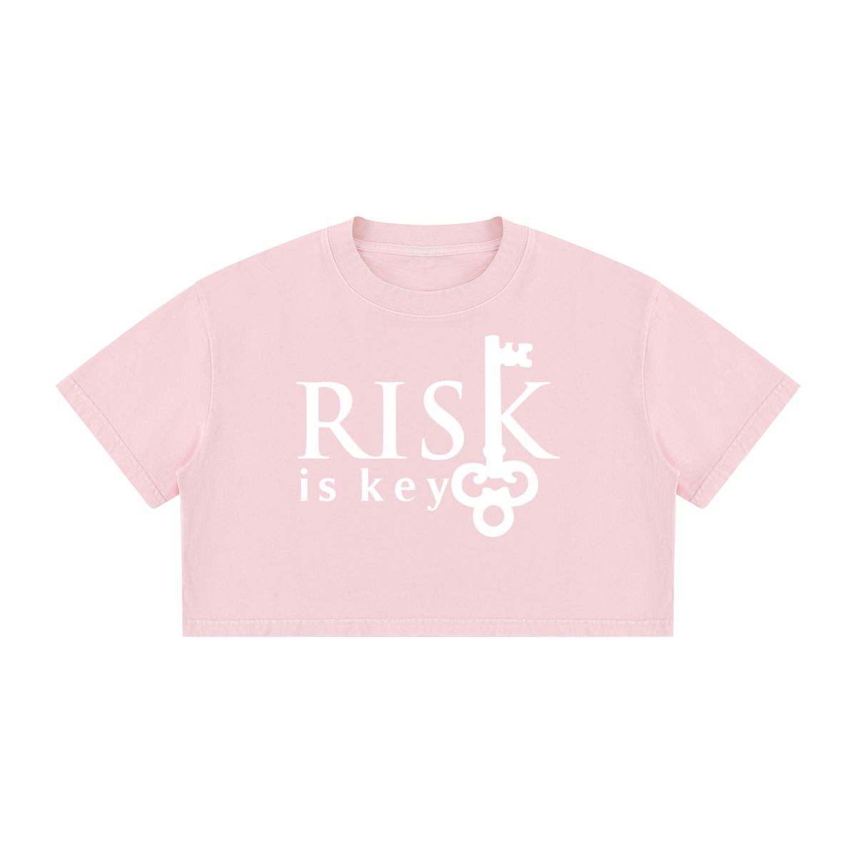 A light pink short-sleeve crop top t-shirt with a white graphic print on the front that reads 'RISK is key' alongside a vintage key illustration, shown against a plain white background.