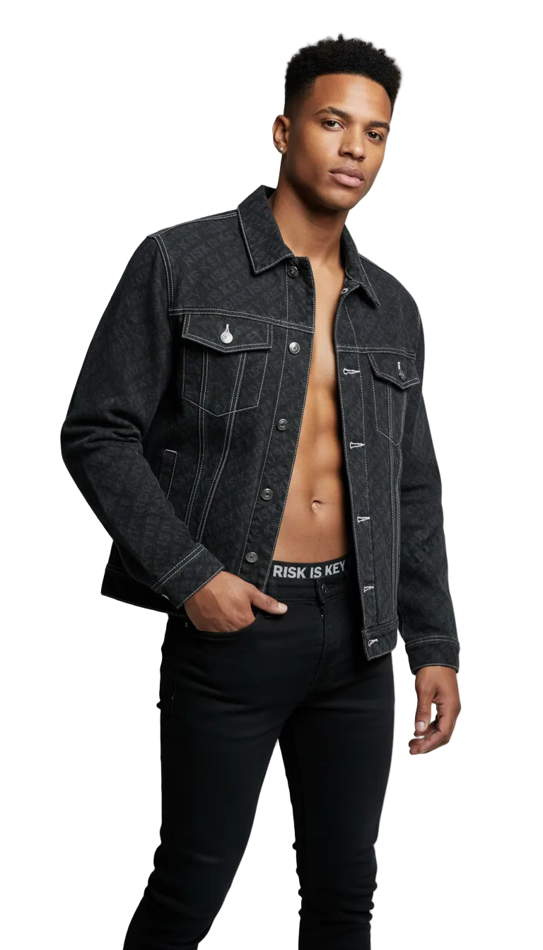 Front view of the Gen Z male Pack Leader in black denim streetwear jacket featuring an all-over white Risk Is Key logo print and classic trucker style button-up front.