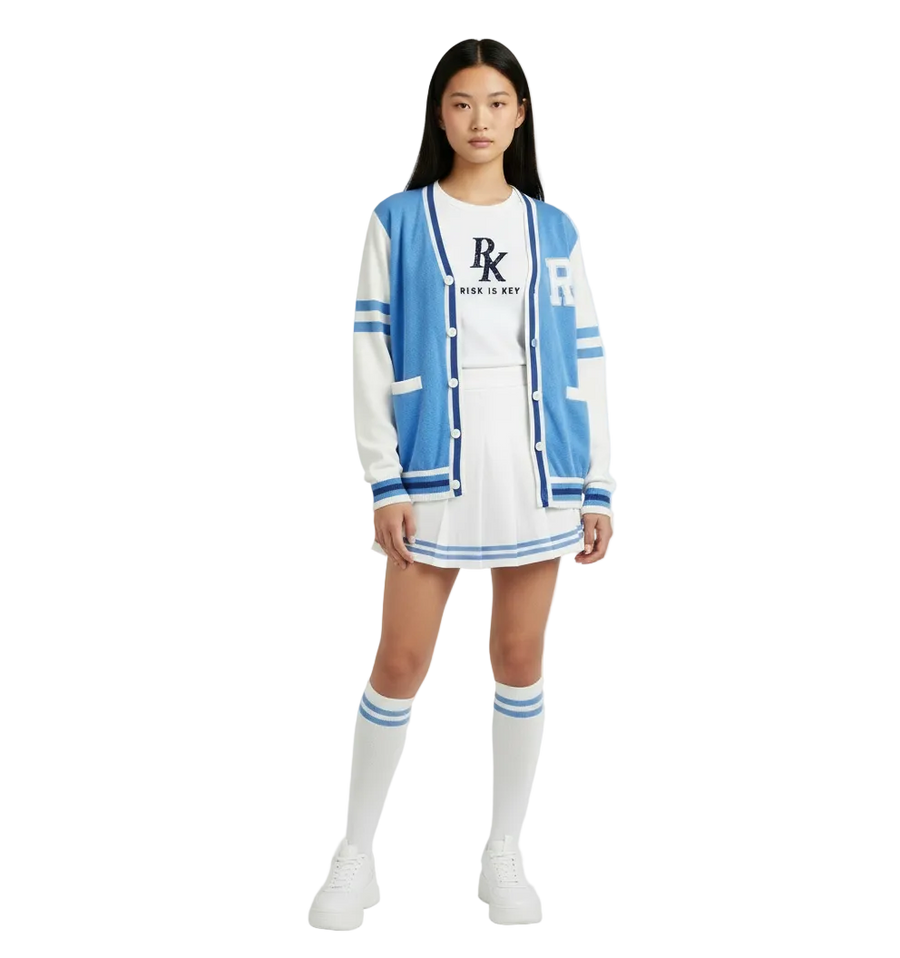 Female model wearing the Risk is Key Unleashed blue and white varsity cardigan with a white pleated skirt, striped knee socks and sneakers.
